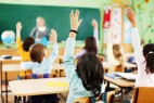 Children are raised hands in classroom.